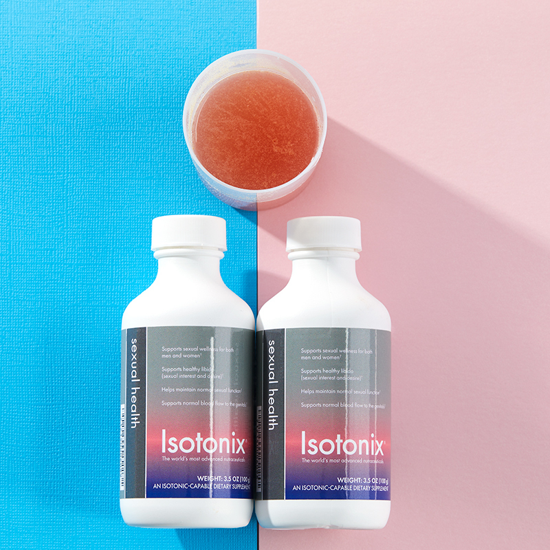 Two botthes of Bottle of Isotonix Sexual Health lying on their sides, one over pink background and the other over blue, with cup above half full
