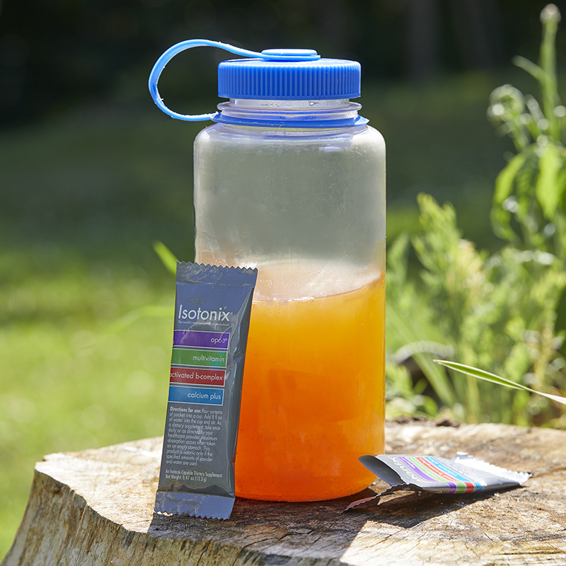 Isotonix Daily Essentials Packets, shown mixed in a water bottle with 2 packets on either side 