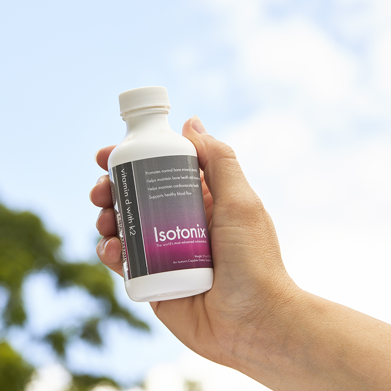 Isotonix Vitamin D with K2, bottle being held up in the air.