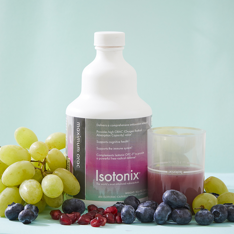 Isotonix Maximum ORAC Formula, with liquid serving cup partially filled, surrounded by grapes