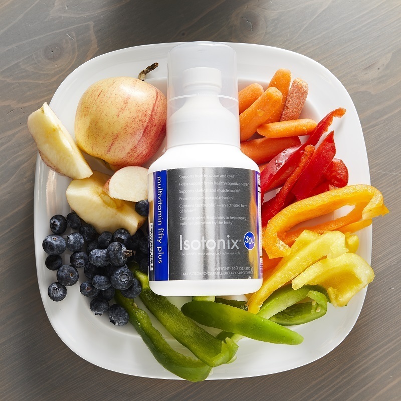 Isotonix Multivitamin Fifty Plus bottle shown with Vegetables and fruit on a white plate