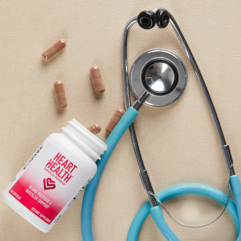 Heart Health Blood Pressure and Vascular Support, capsules spilled next to a blue stethoscope