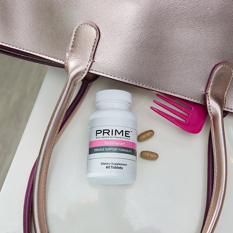 Prime Feminene Female Support Formula, bottle lying next to a purse, comb and caplets
