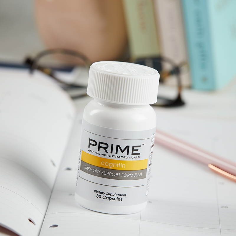 Prime Cognitin Memory Support Formula, bottle sitting on a notebook with reading glasses and a pen