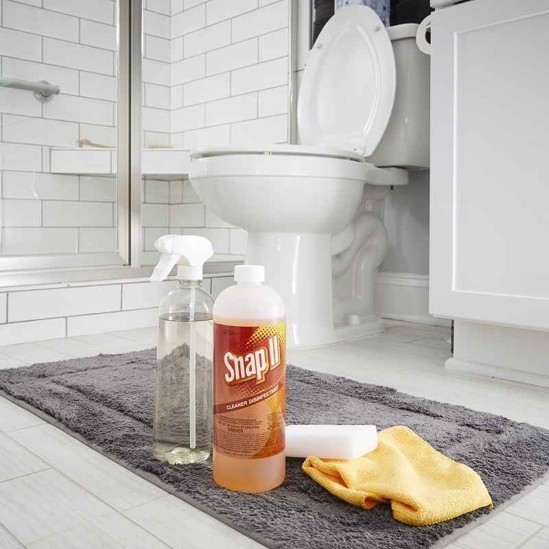 Snap II Cleaner Disinfectant bottle, with spray bottle and towel on bathroom floor