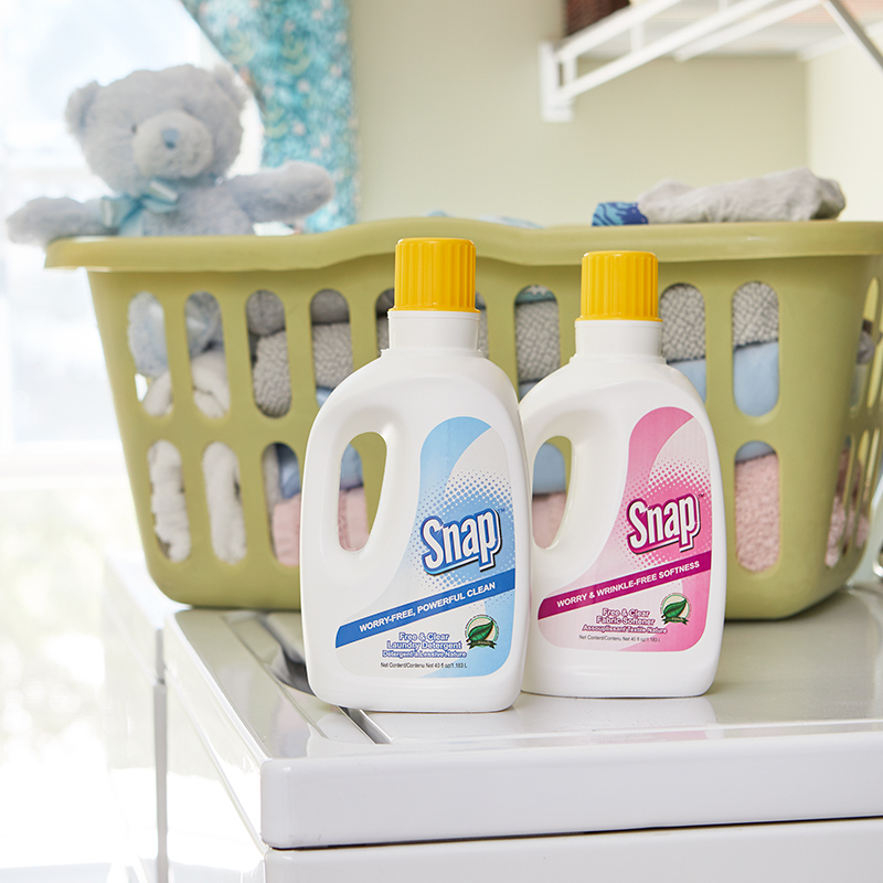 Snap Free & Clear Laundry products, Detergent and Fabric Softener, next to a laundry basket filled with towels and Teddy Bear