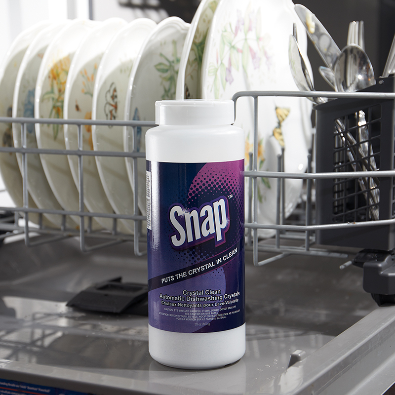 Snap Crystal Clean Automatic Dishwashing Crystals bottle, sitting on open dishwasher filled with dishes