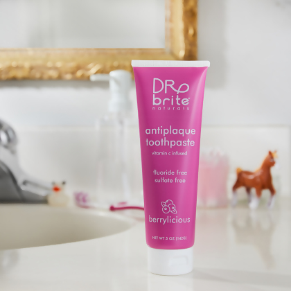Dr. Brite Kids Anti-Plaque Toothpaste with Vitamin C tube, on a bathroom sink, mirror in back and a toy plastic horse