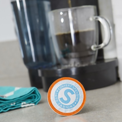 Shopping Annuity Brand Premium Coffee, pod shown with coffee maker and tea towel