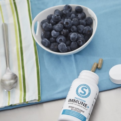 Shopping Annuity Brand Premium Immune + Formula, caplets on a blue tea towel with blueberries