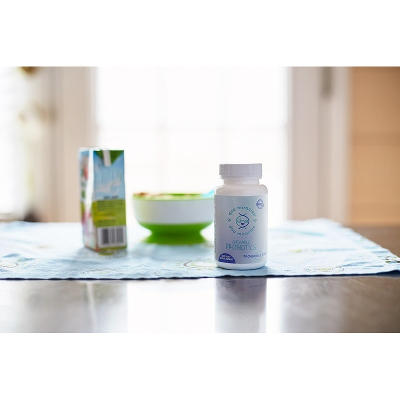 DNA Miracles Chewable Probiotics on a table with a juice box and a bowl and spoon on a blue placemat