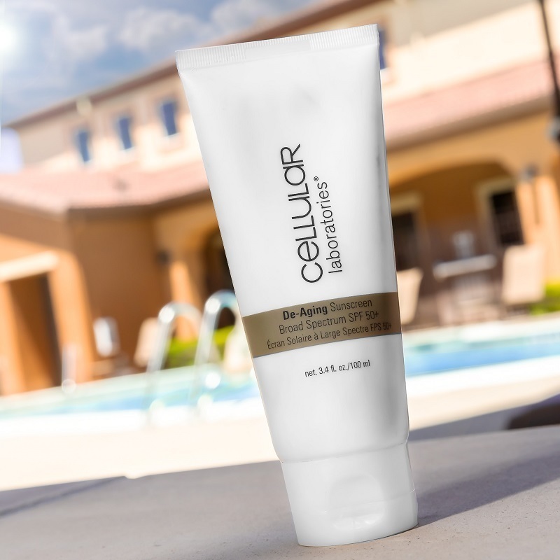 Cellular Laboratories De-Aging Sunscreen Broad Spectrum SPF 50+ tube, with a swimming pool nearby