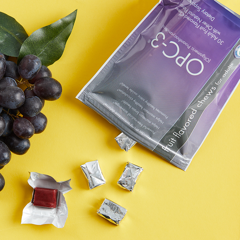 OPC-3 Chews, opened bag with chews and red grapes on a yellow table