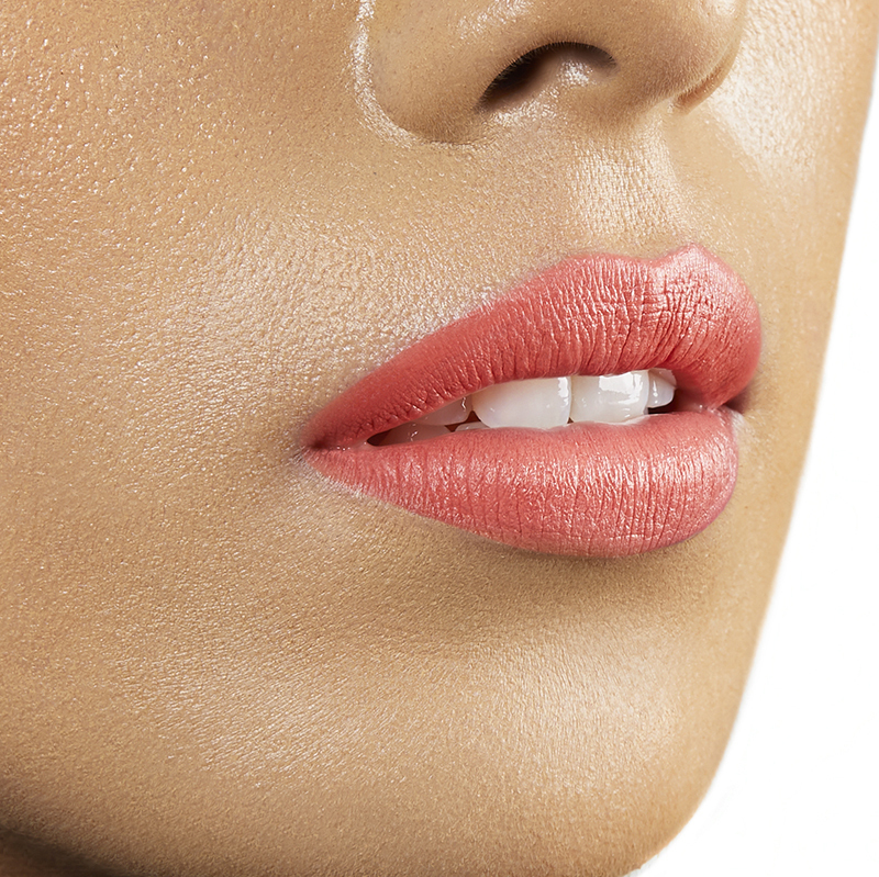 Closeup on lips of model with medium skin tone wearing Motives Cream Lipstick, color Peachy Keen