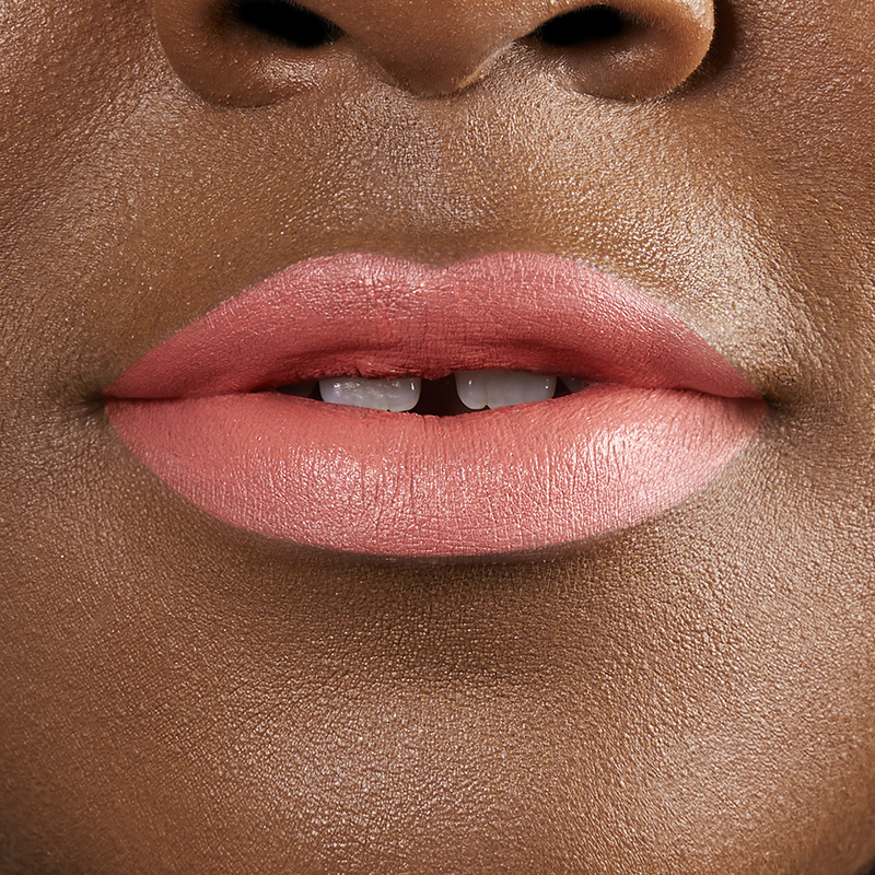 Closeup on lips of model with dark skin tone wearing Motives Cream Lipstick, color Peachy Keen