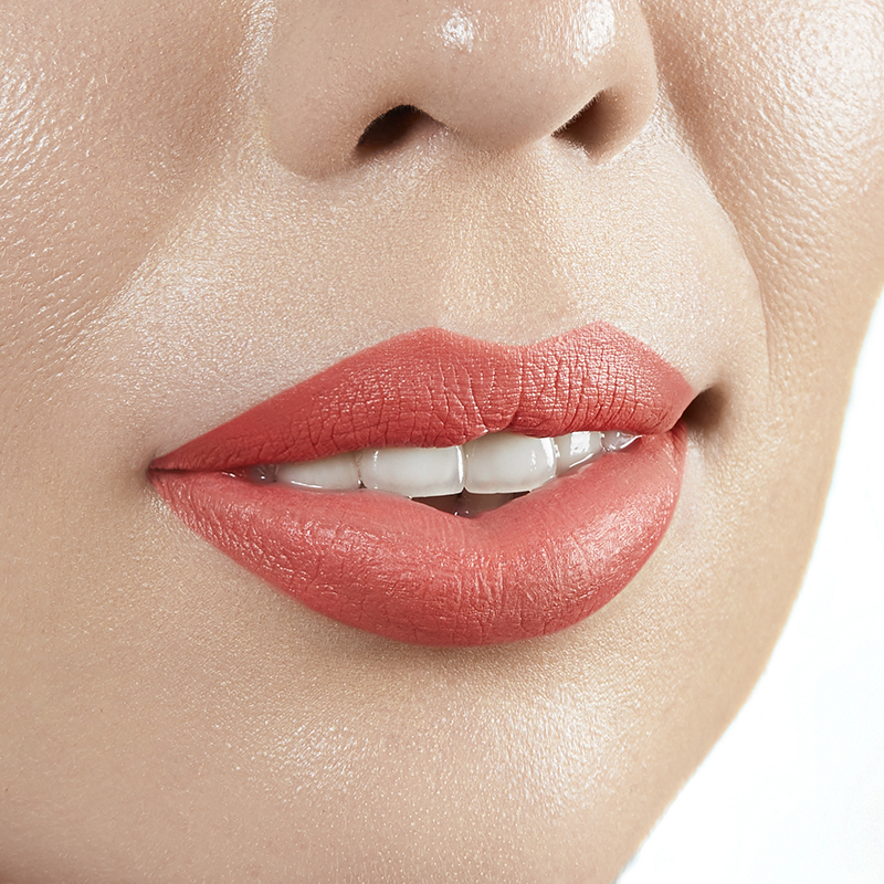 Closeup on lips of model with light skin tone wearing Motives Cream Lipstick, color Peachy Keen