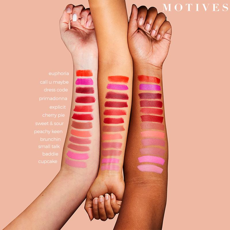 Motives Motives Cream Lipstick, shown as stripes of colors on three models' arms of light, medium and dark skin tones.