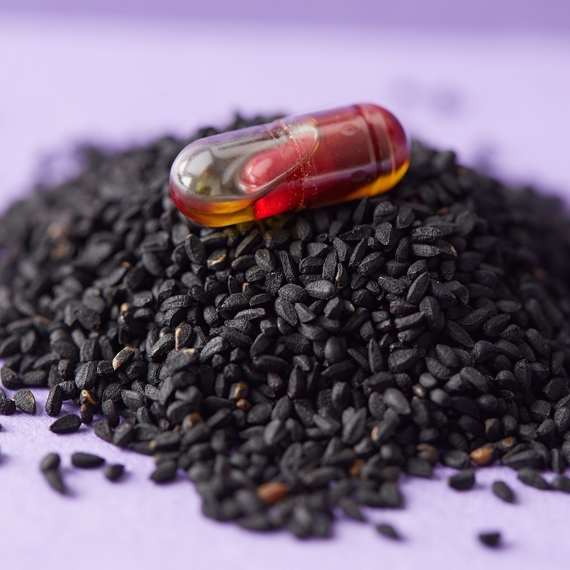 Thymenol capsule on top of a pile of black cumin seeds
