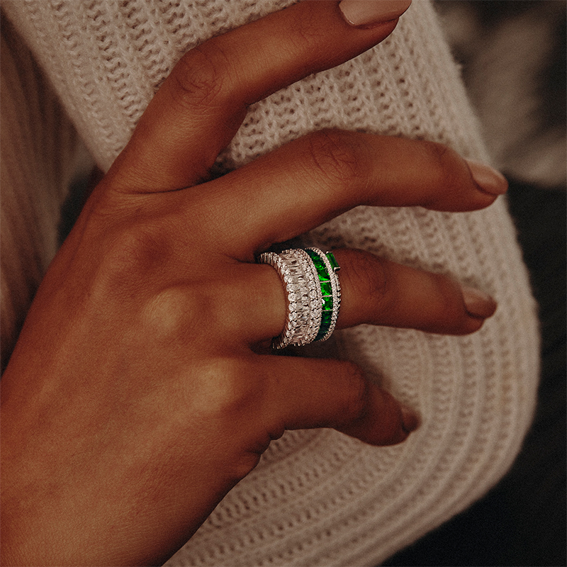 Model wearing Layered AMBER - Emerald Cut Eternity Band in silver with clear gems, stacked with other rings