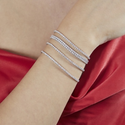 Closeup of model wearing 5 stacked Layered BRIA Round Cut Tennis Bracelets in silver