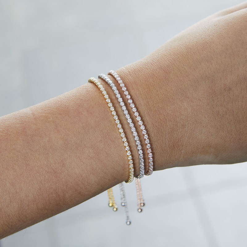 Closeup of model wearing 3 stacked Layered BRIA Round Cut Tennis Bracelets, one each in gold, silver and rose gold