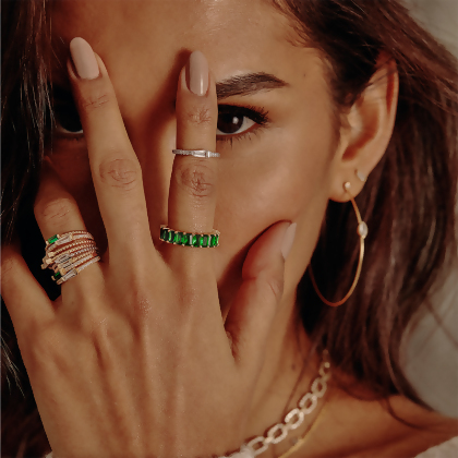 Model wearing 8 Layered Adrienne - Spiraled Baguette Rings, stacked, with green stones and clear stones, in gold, with other jewelry