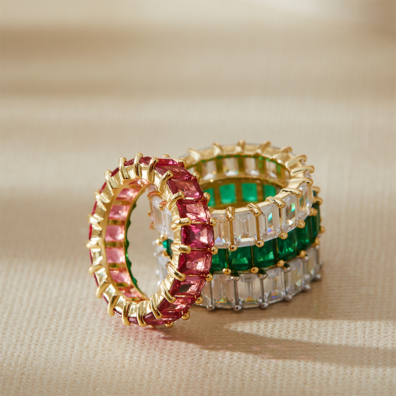 Closeup example of several Layered AMBER - Emerald Cut Eternity Band, in gold, with pink, green and clear gems