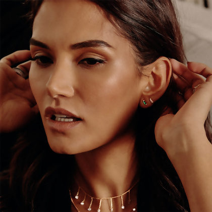 Model wearing 2 pairs of Layered ISABELLA - Baguette Mini Studs earrings in both Gold with Clear Gem and Gold with Green Gem, and a necklace