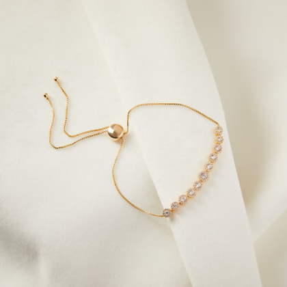 Layered Kelly - Bezel Bracelet in gold, with slip clasp, on a cream colored surface