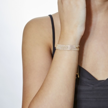 Model wearing 5 stacked Layered BRIA Round Cut Tennis Bracelets in gold