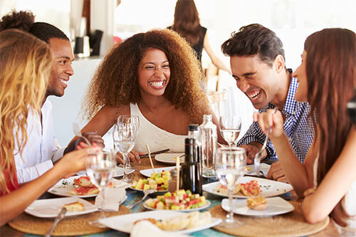 Group of people gathered by the table enjoying a meal together.