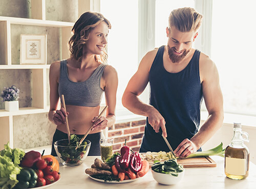 Two people preparing a salad in a kitchen and smiling.